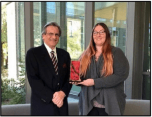 A woman holding a plaque standing next to an older man.
