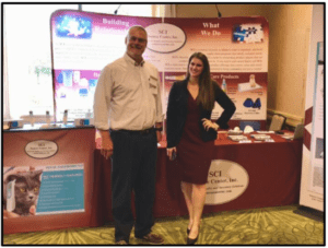 Two people posing at a trade show booth