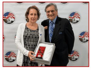 Two people holding an award, smiling together.