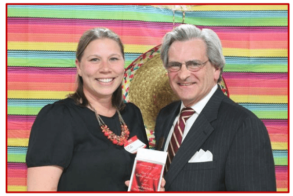 Two smiling people in formal attire against a colorful striped background.