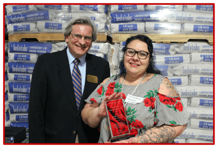 Two people smiling, one holding a red gift bag in a store.