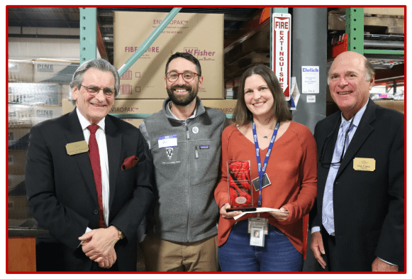 Four professionals posing together in a workplace setting.