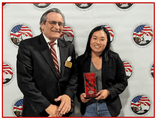 Two people posing with an award at an event.