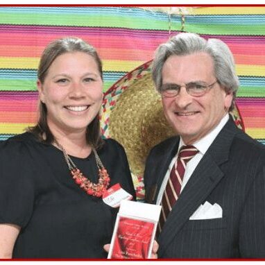 Two people smiling in front of decorations.