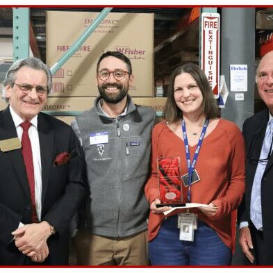 Four people smiling with an award plaque.