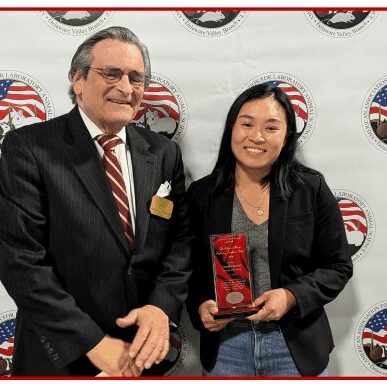 Two people smiling with award plaque.
