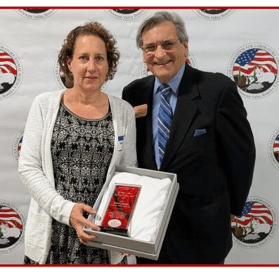 Two people holding an award, smiling together.
