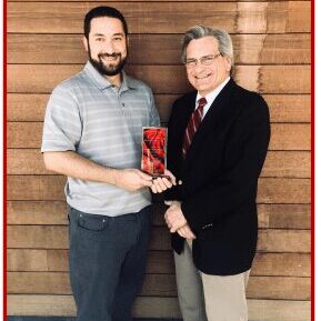 Two men holding an award, smiling.