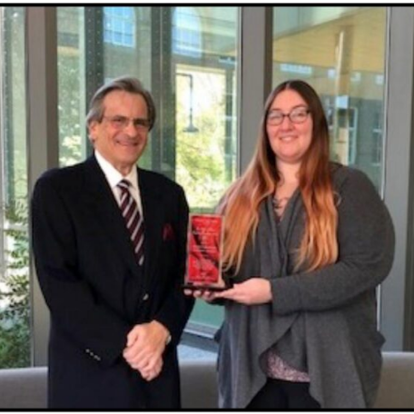 A woman holding a plaque standing next to an older man.