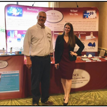 Two people posing at a trade show booth
